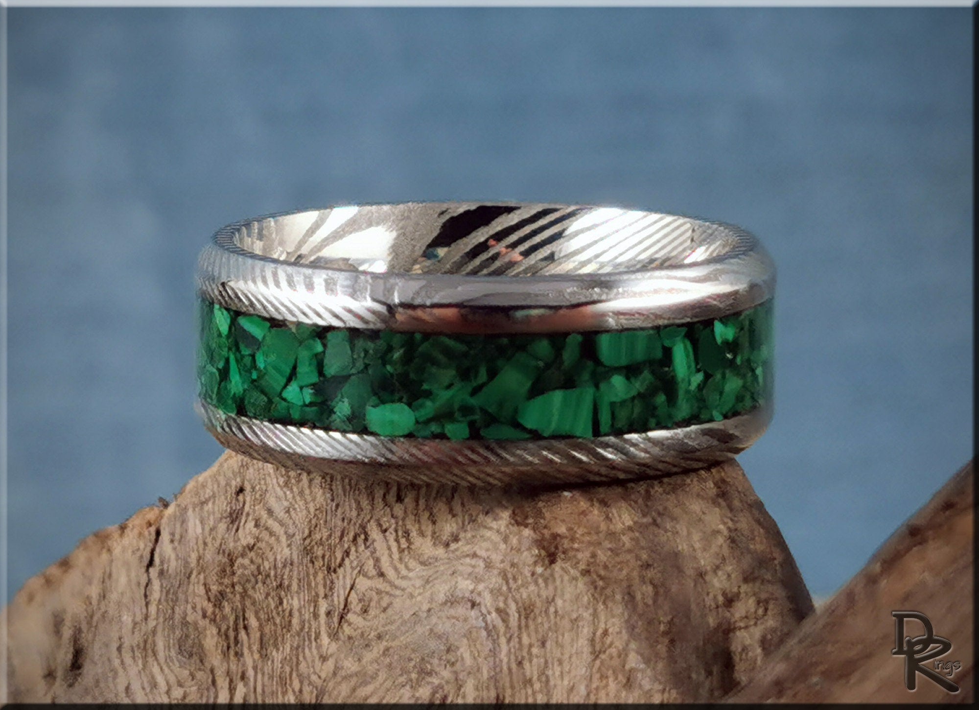 Damascus steel ring with malachite inlay featuring green stone chips and polished metal finish
