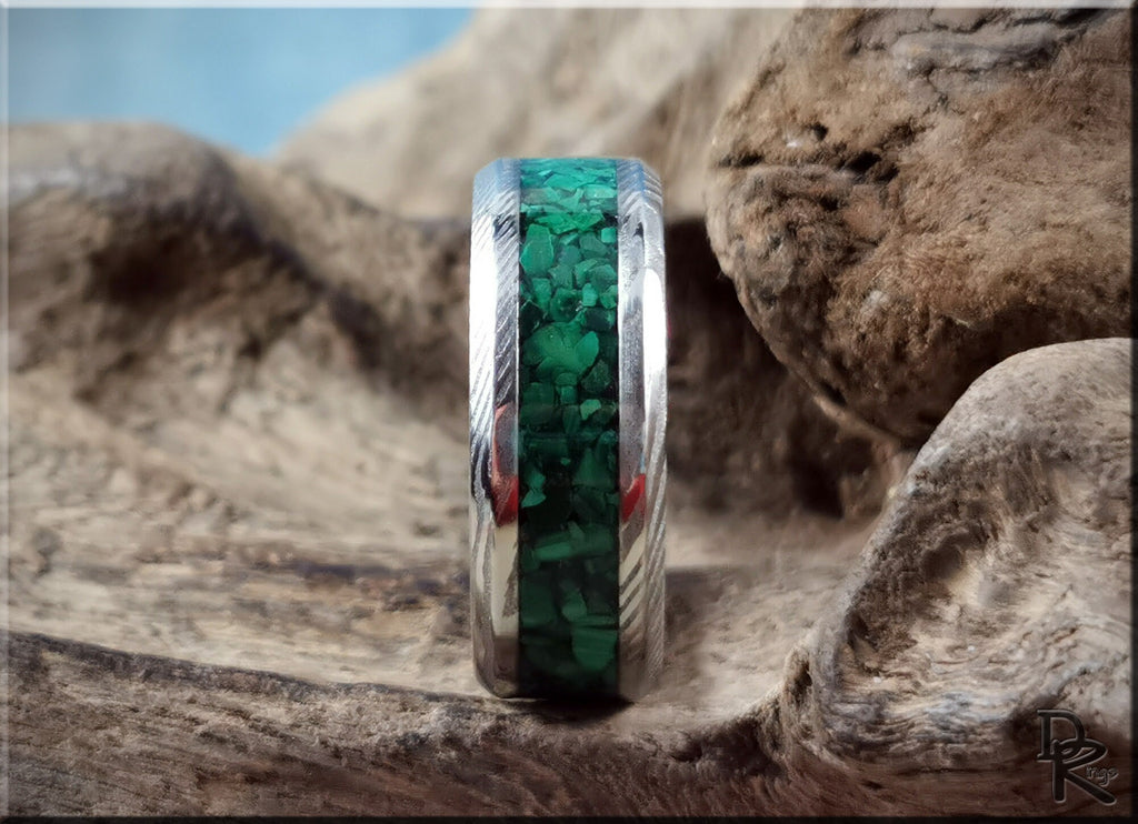 Damascus steel ring with malachite inlay featuring intricate patterns and vibrant green stones