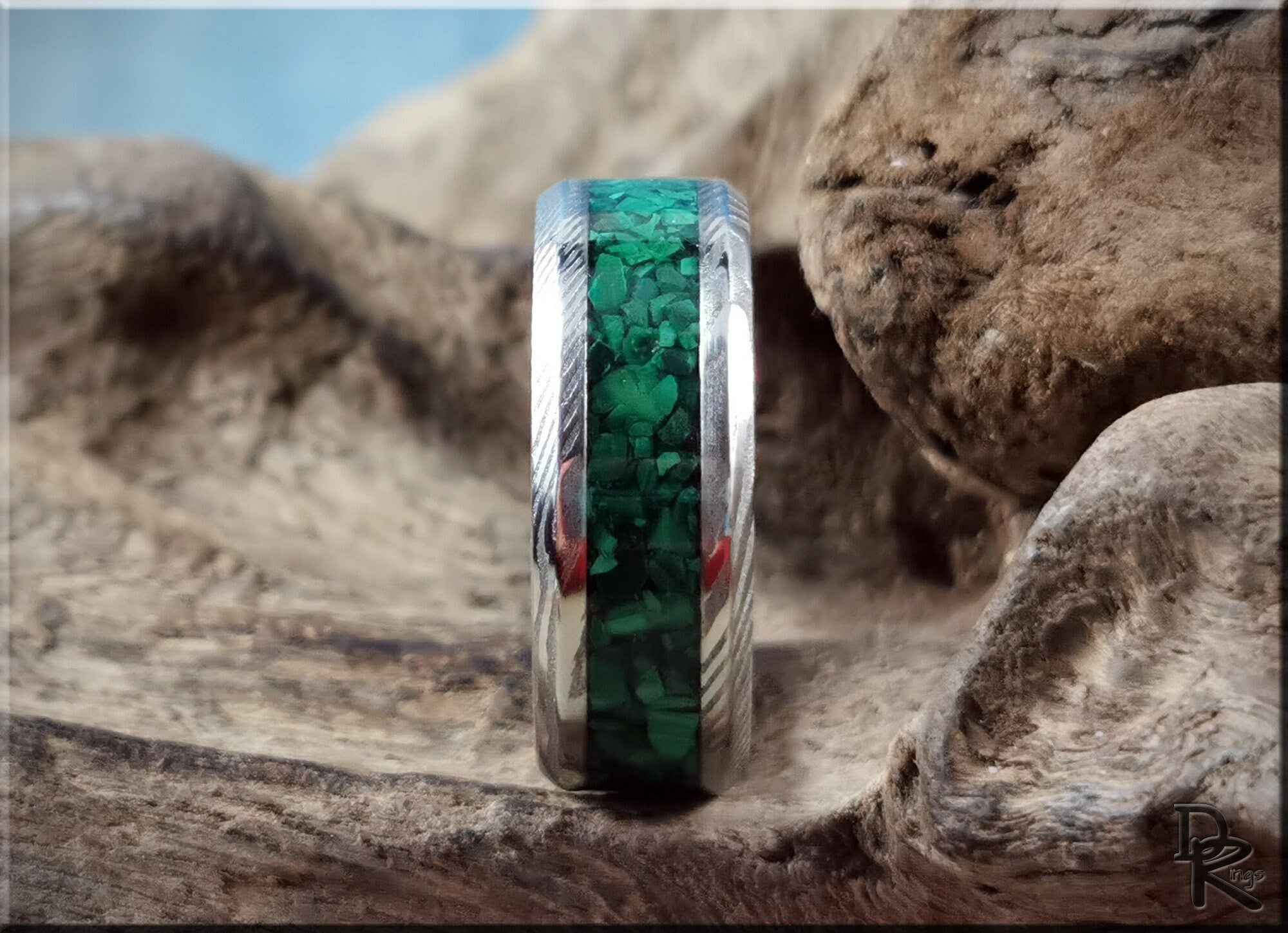Damascus steel ring with malachite inlay featuring intricate patterns and vibrant green stones
