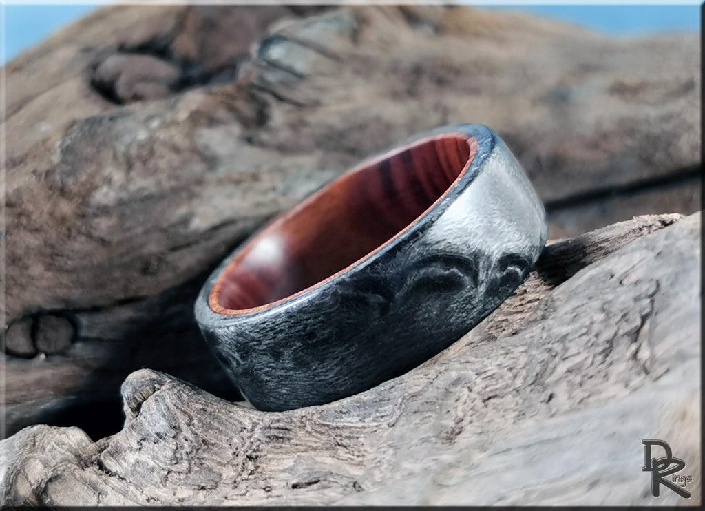 DR Rings grey maple ring with textured grey exterior and smooth polished wood interior on rustic wood