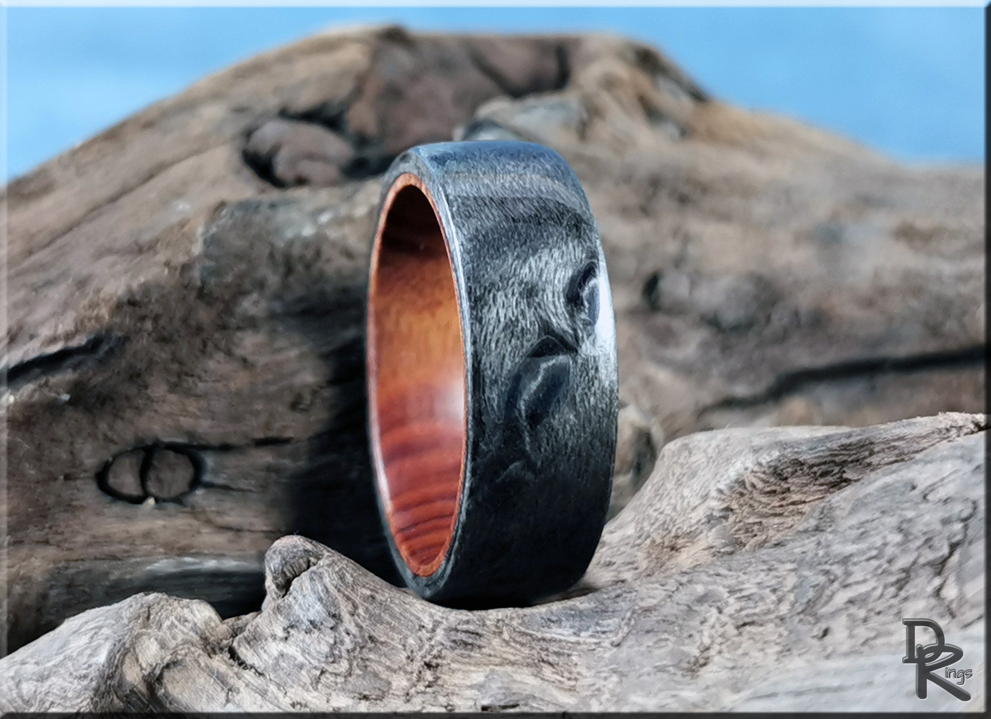 Grey maple ring by DR Rings with textured wood grain finish displayed on natural wood background