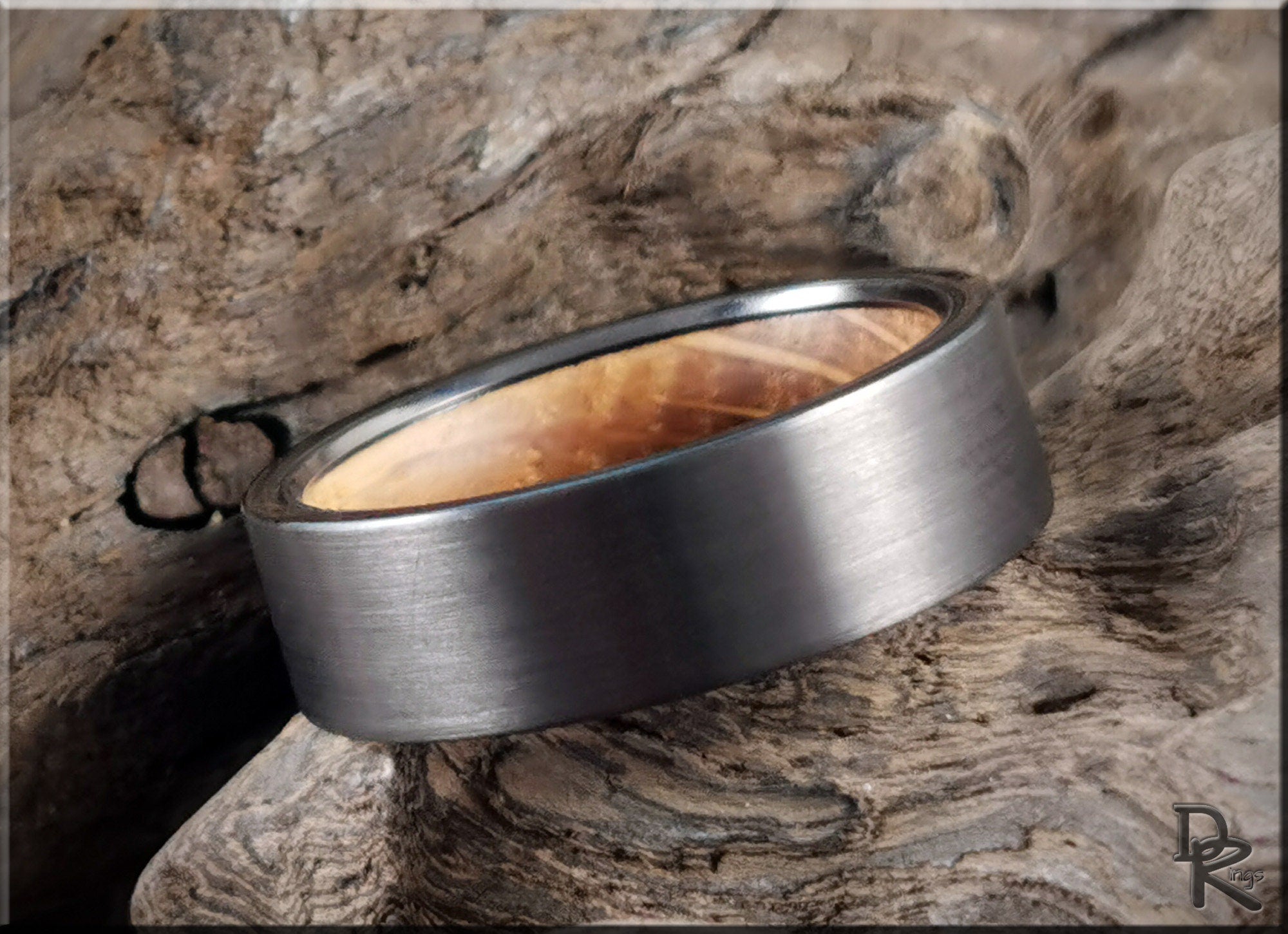 DR Rings gun metal tungsten ring with brushed finish placed on textured wooden surface