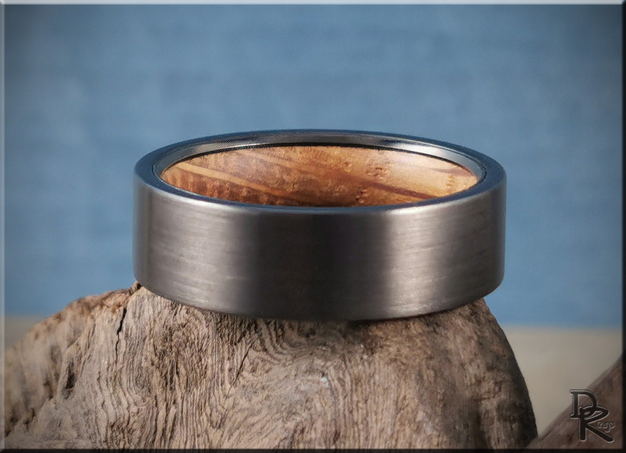 DR Rings gun metal tungsten ring with a brushed finish and wooden interior on textured wood