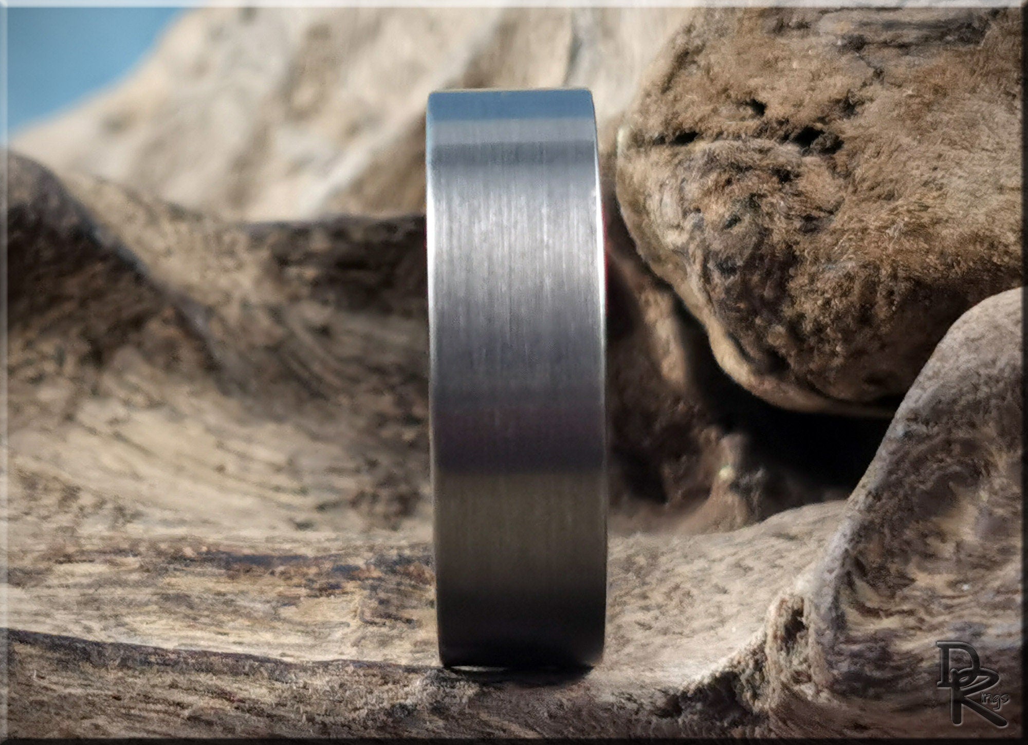 Gun metal tungsten ring with brushed finish displayed on natural wood background by DR Rings