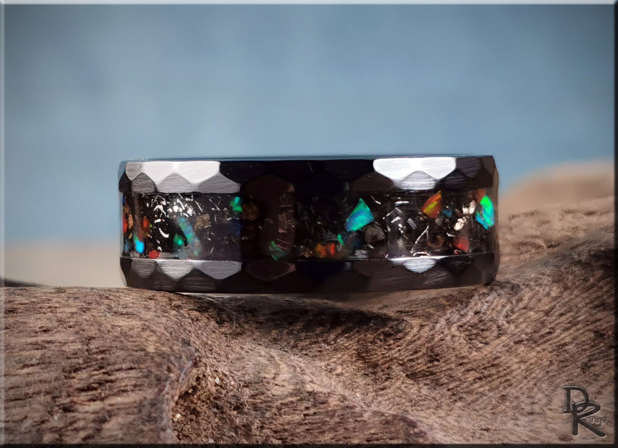 Hammered ceramic ring with inlay featuring colorful opal accents and a textured black band