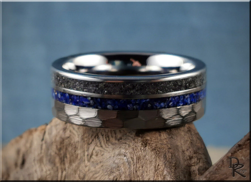 Hammered tungsten ring with two inlays featuring blue and black textured bands on a wooden surface
