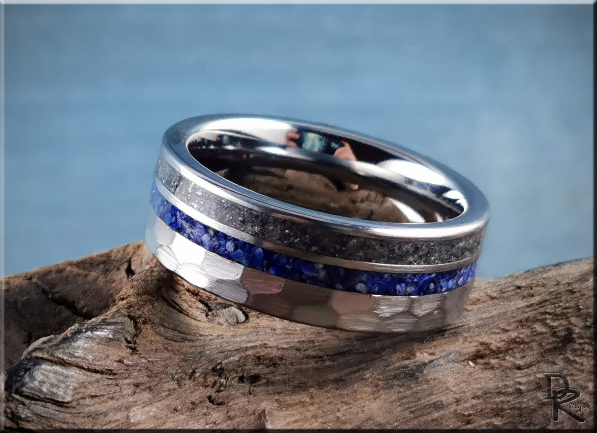 Hammered tungsten ring with two inlays featuring silver and blue textured bands on wood