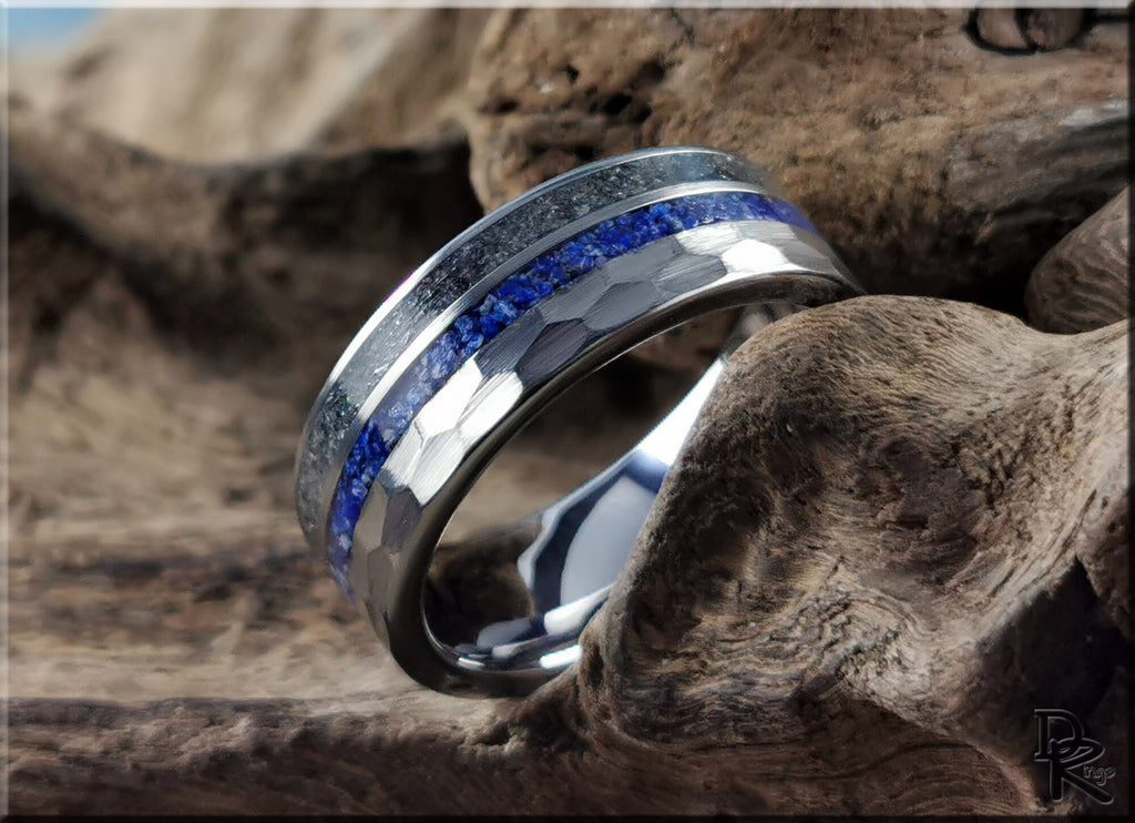 Hammered tungsten ring with two inlays featuring blue and silver bands on a rustic wooden background