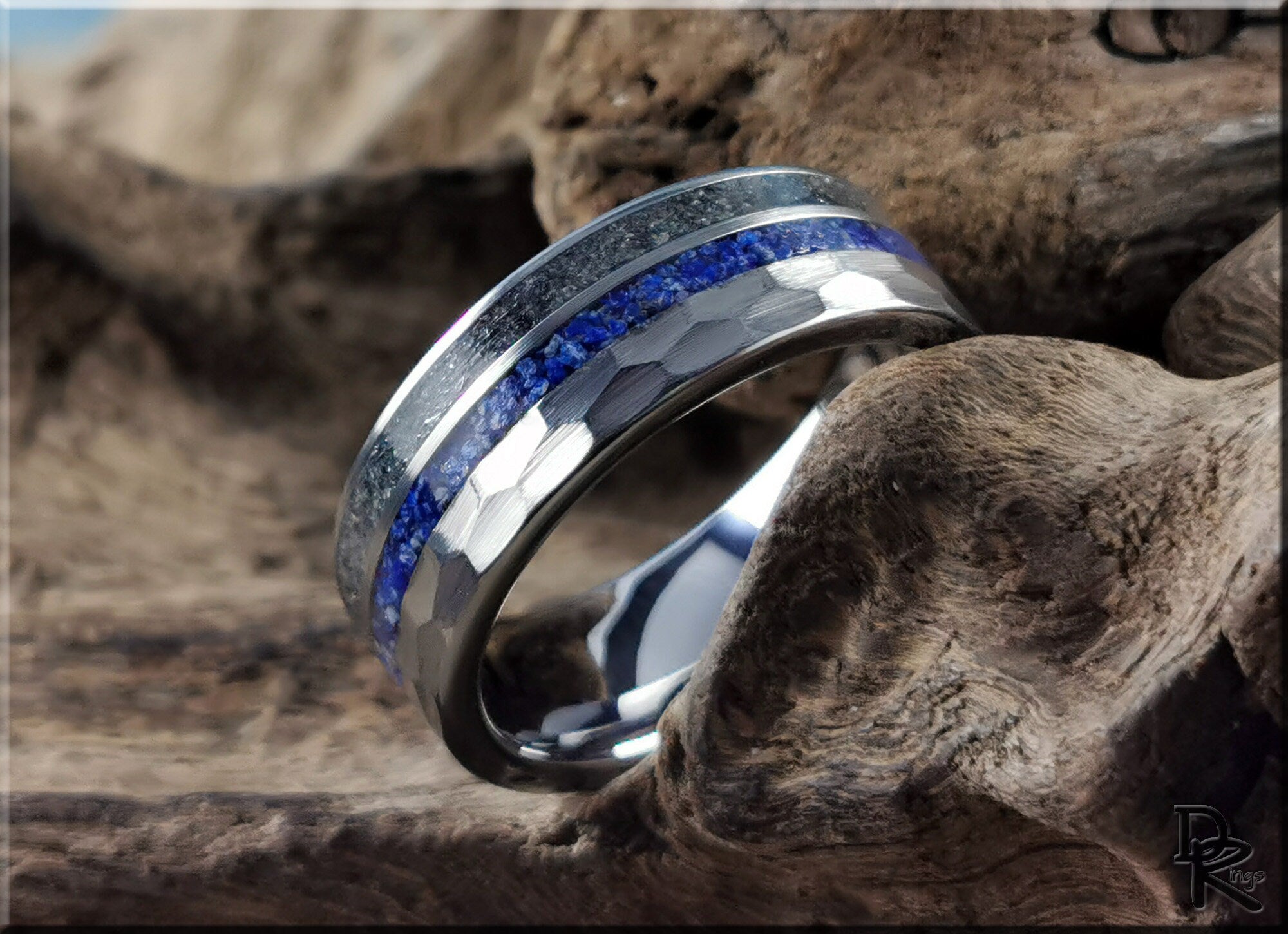 Hammered tungsten ring with two inlays featuring blue and silver bands on a rustic wooden background