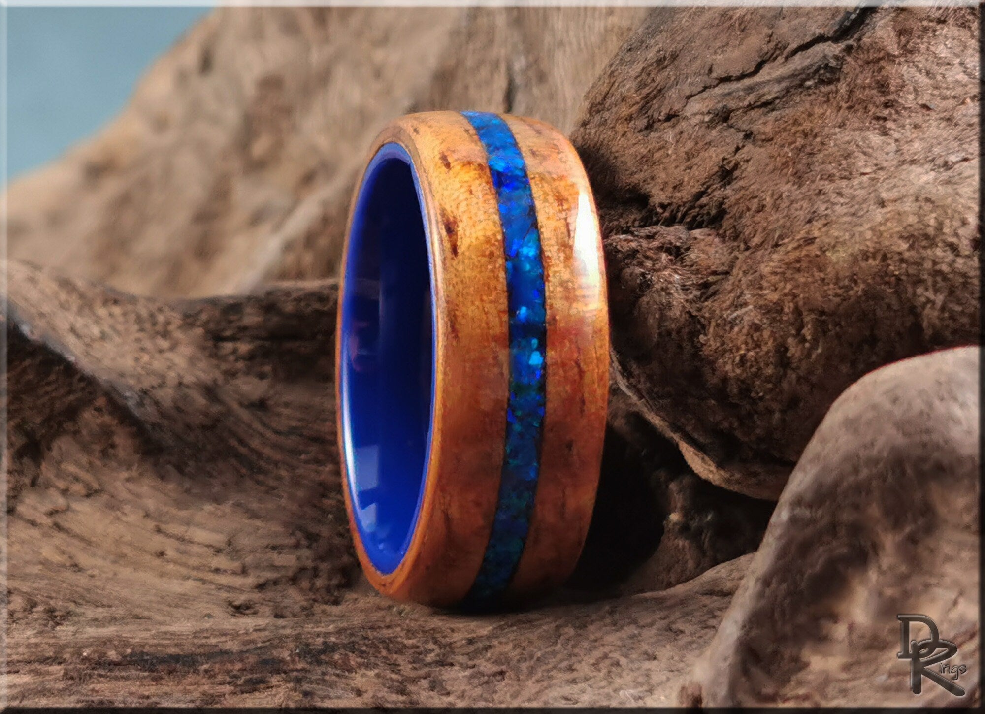 Koa wood ring with opal and ceramic blue inlay by DR Rings on natural wood background