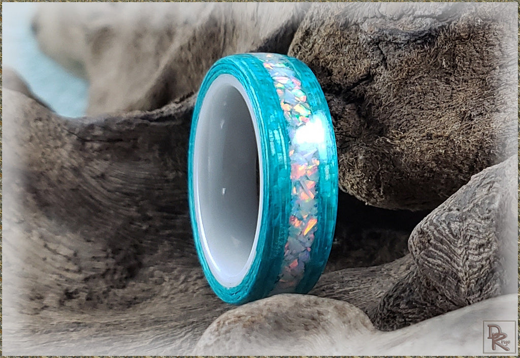 DR Rings opal inlay wood ring with vibrant blue and iridescent opal detailing on natural wood background