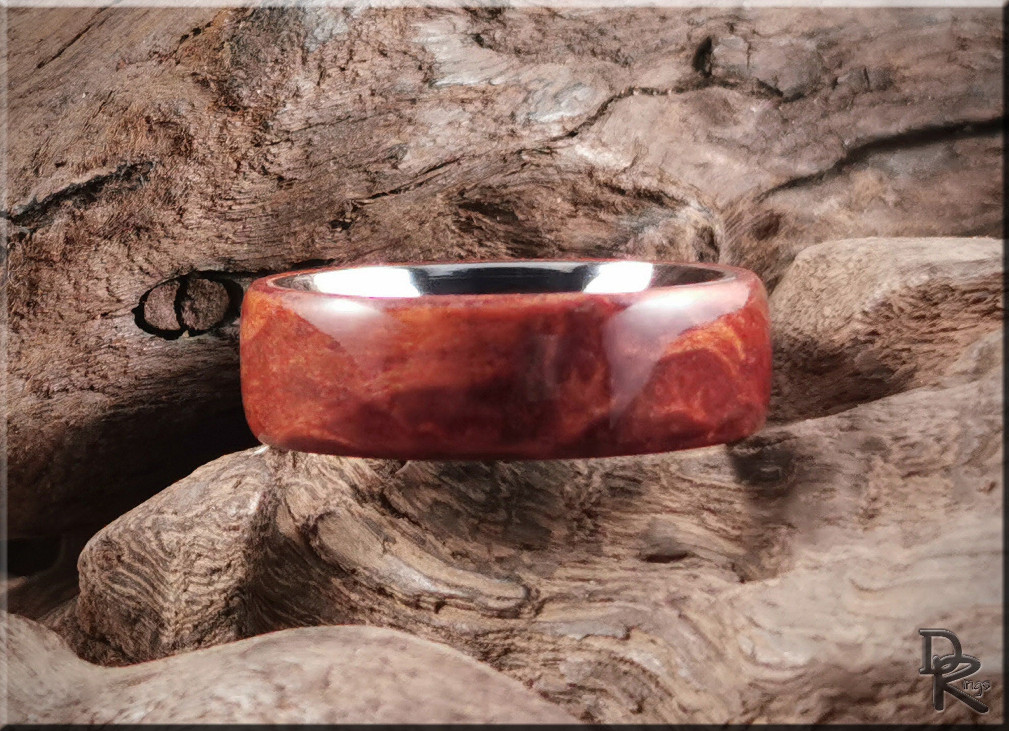 Redwood ring on titanium band with polished finish displayed on natural wood background