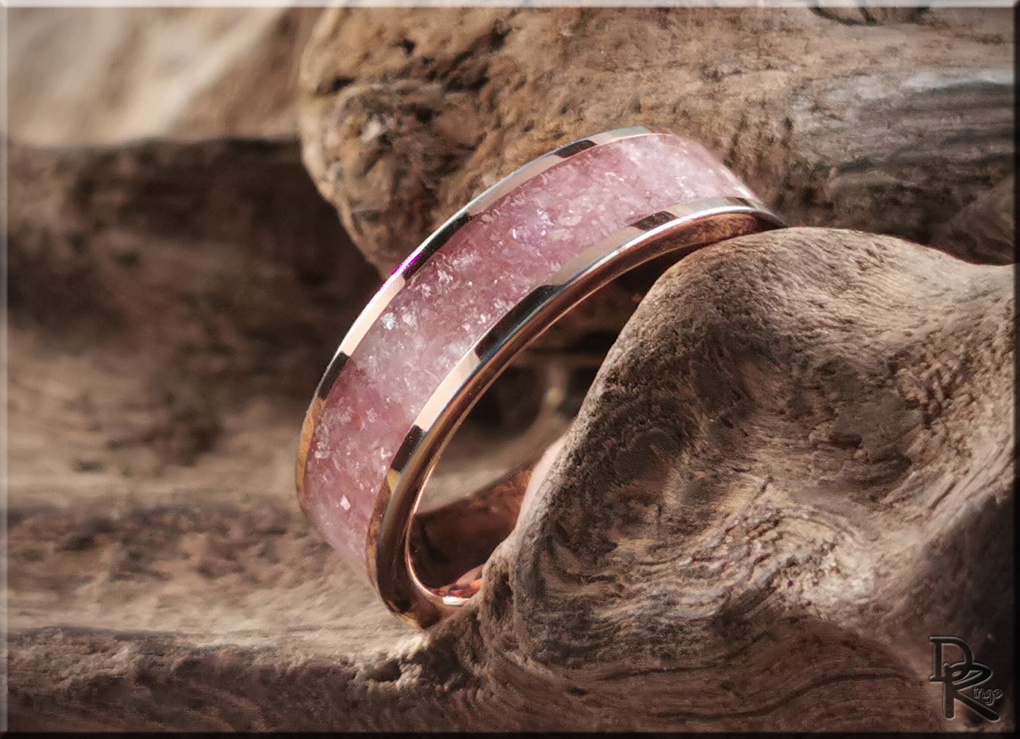 Rose tungsten ring with lepidolite featuring a pink stone inlay on a rustic wood background