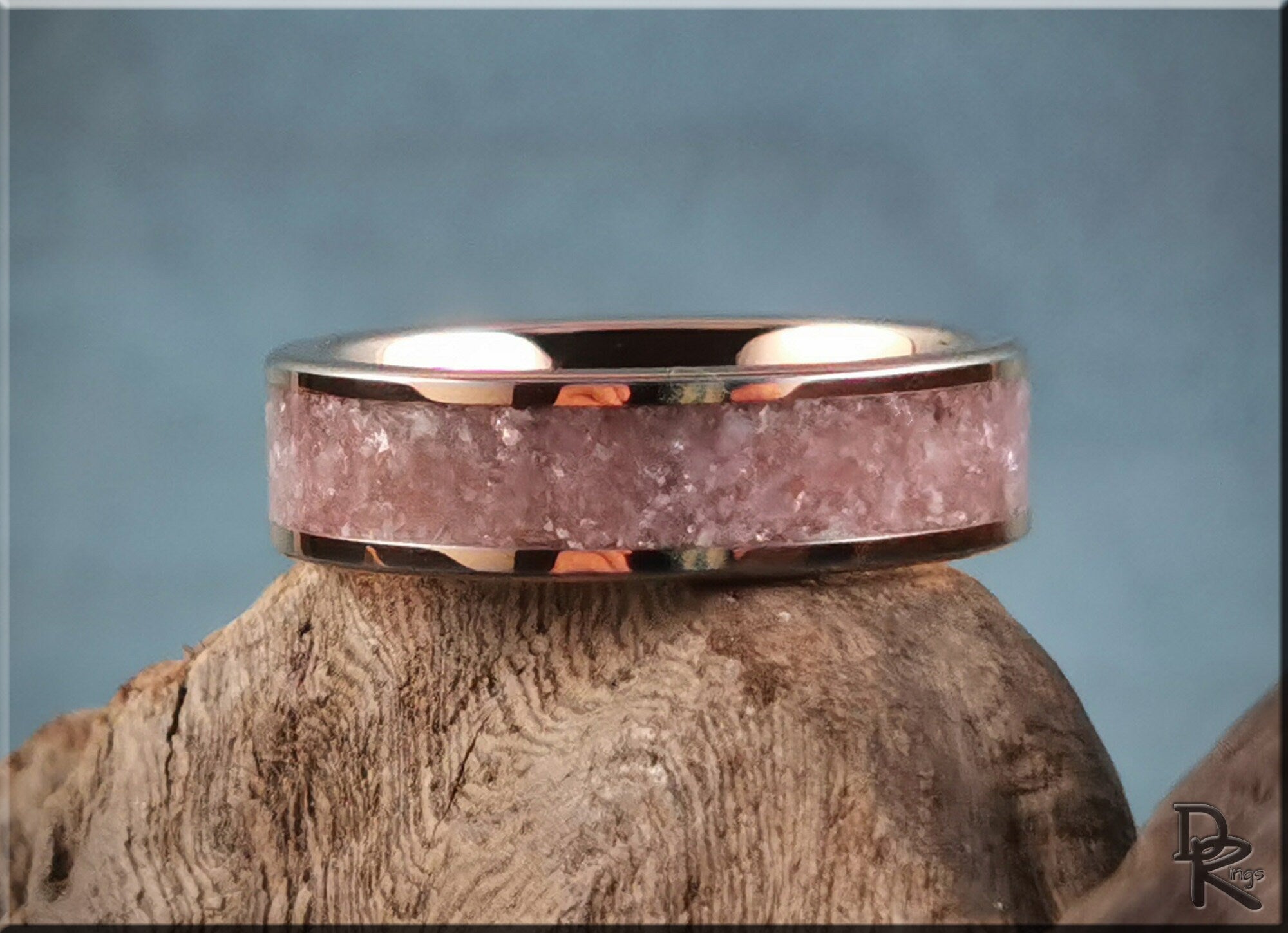 Rose tungsten ring with lepidolite inlay featuring a polished finish displayed on textured wood