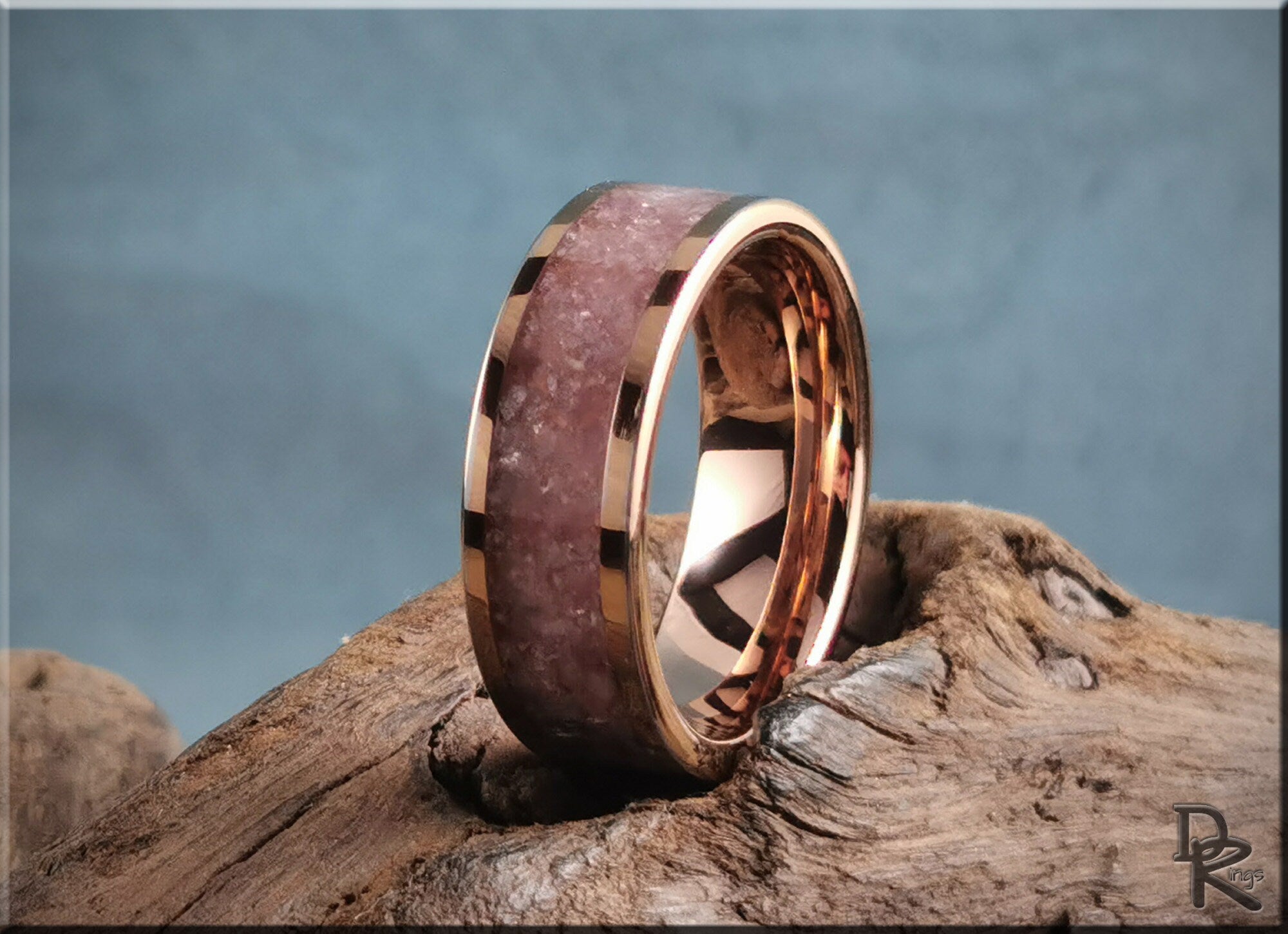Rose tungsten ring with lepidolite stone inlay from DR Rings placed on rustic wood background
