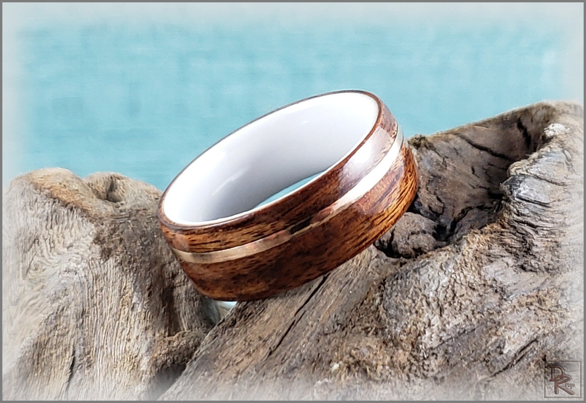 Rosewood ring with wire inlay resting on textured natural wood background by DR Rings