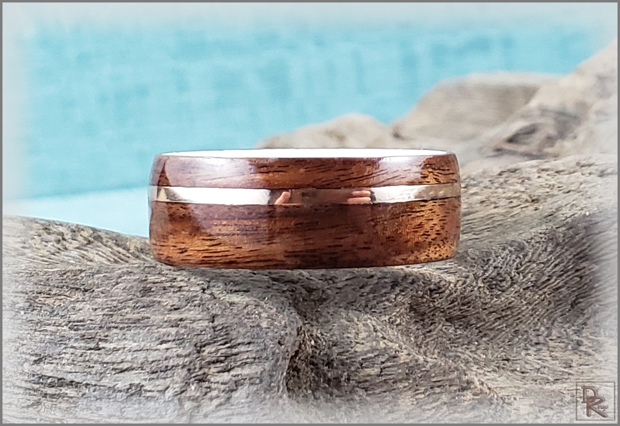 Rosewood ring with wire inlay handcrafted by DR Rings resting on weathered wood