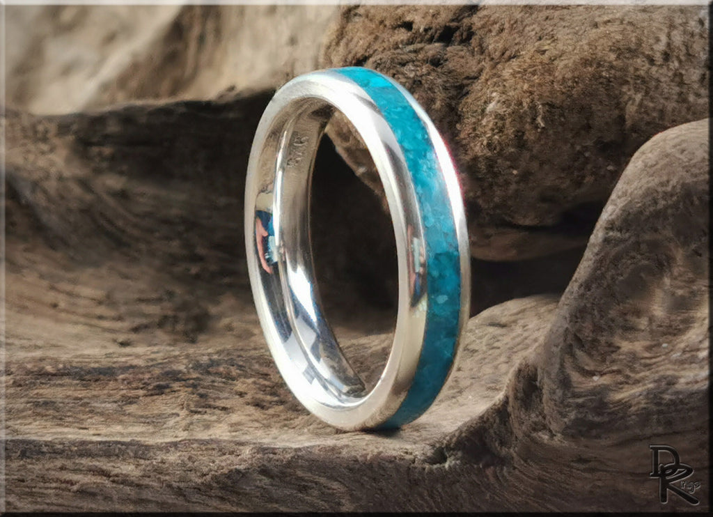 Silver ring with inlay featuring vibrant turquoise stone band on rustic wood background