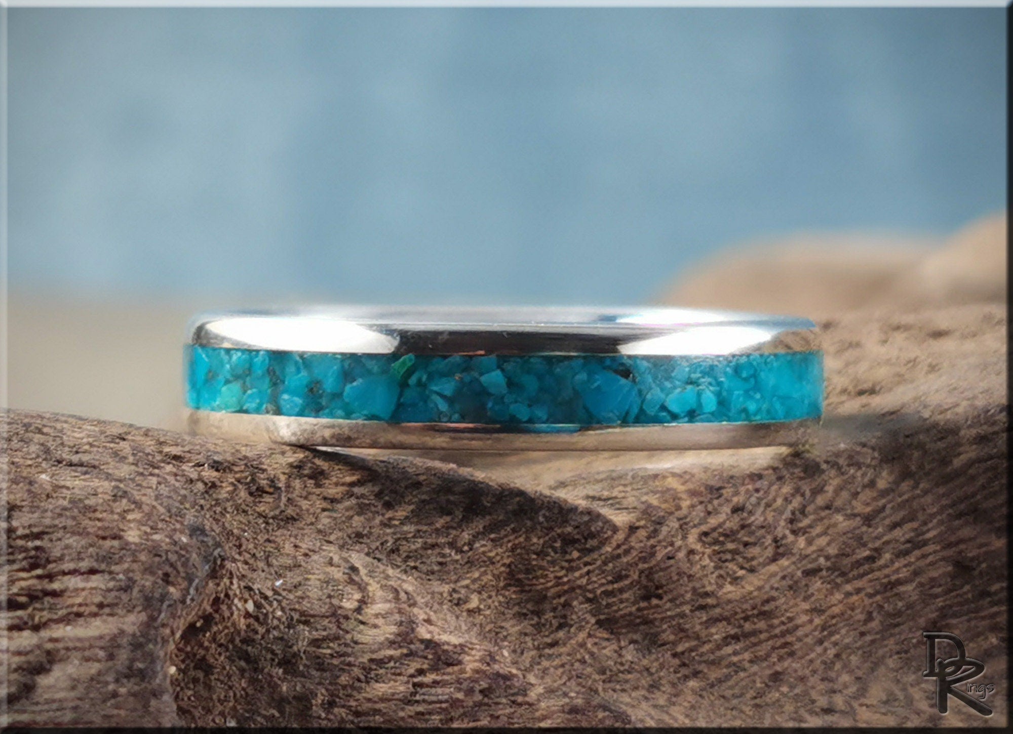 DR Rings silver ring with inlay featuring a turquoise stone center on rustic wood background