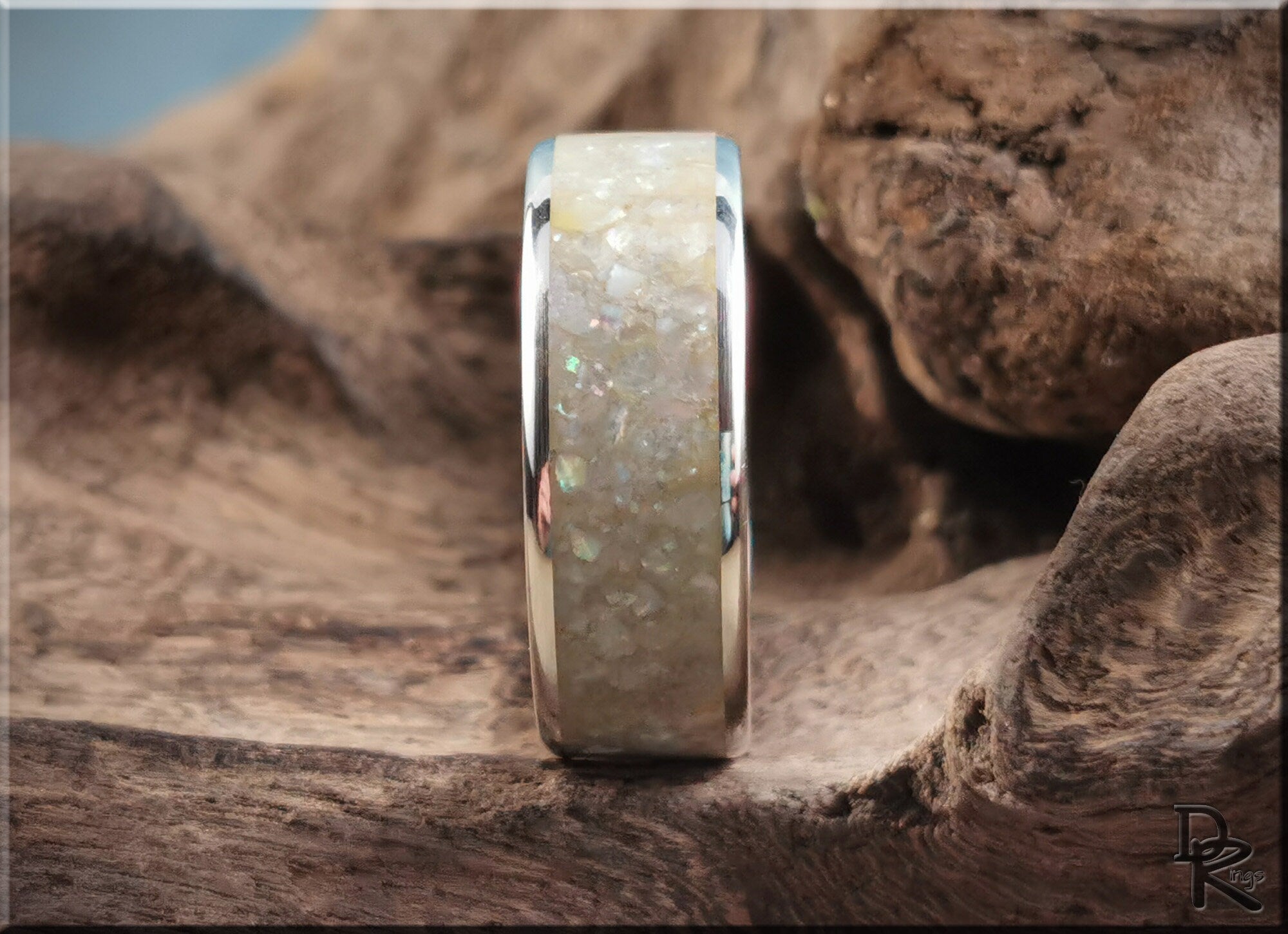 Sterling silver ring with pearl inlay displayed on textured wood surface by DR Rings