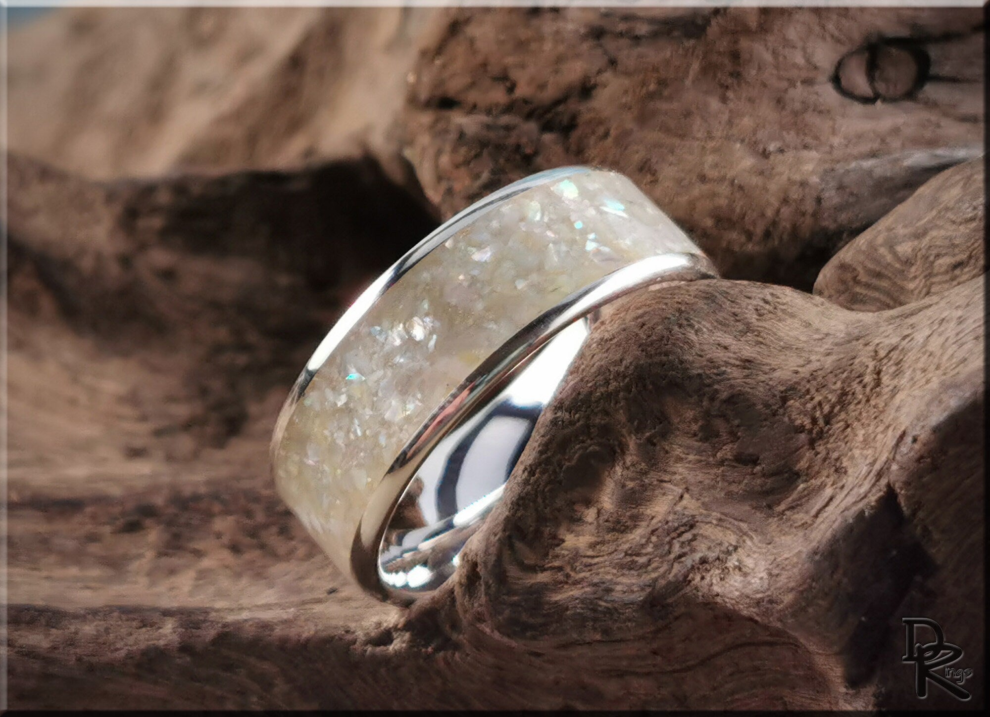 Sterling silver ring with pearl inlay displayed on textured wooden surface by DR Rings