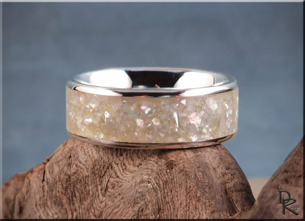 Sterling silver ring with pearl inlay resting on rustic wood background by DR Rings