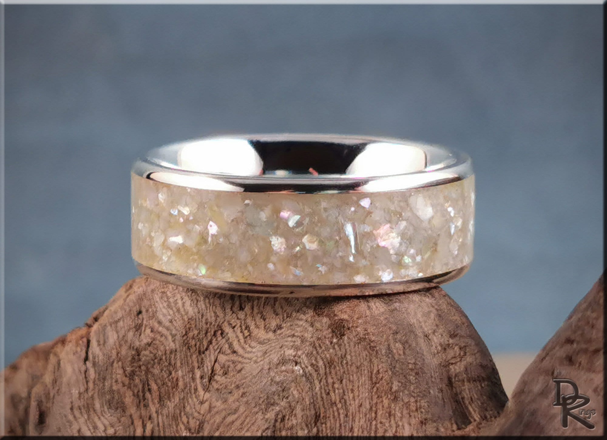 Sterling silver ring with pearl inlay resting on rustic wood background by DR Rings