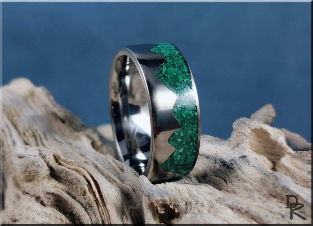 Titanium mountain ring with malachite inlay resting on textured driftwood background