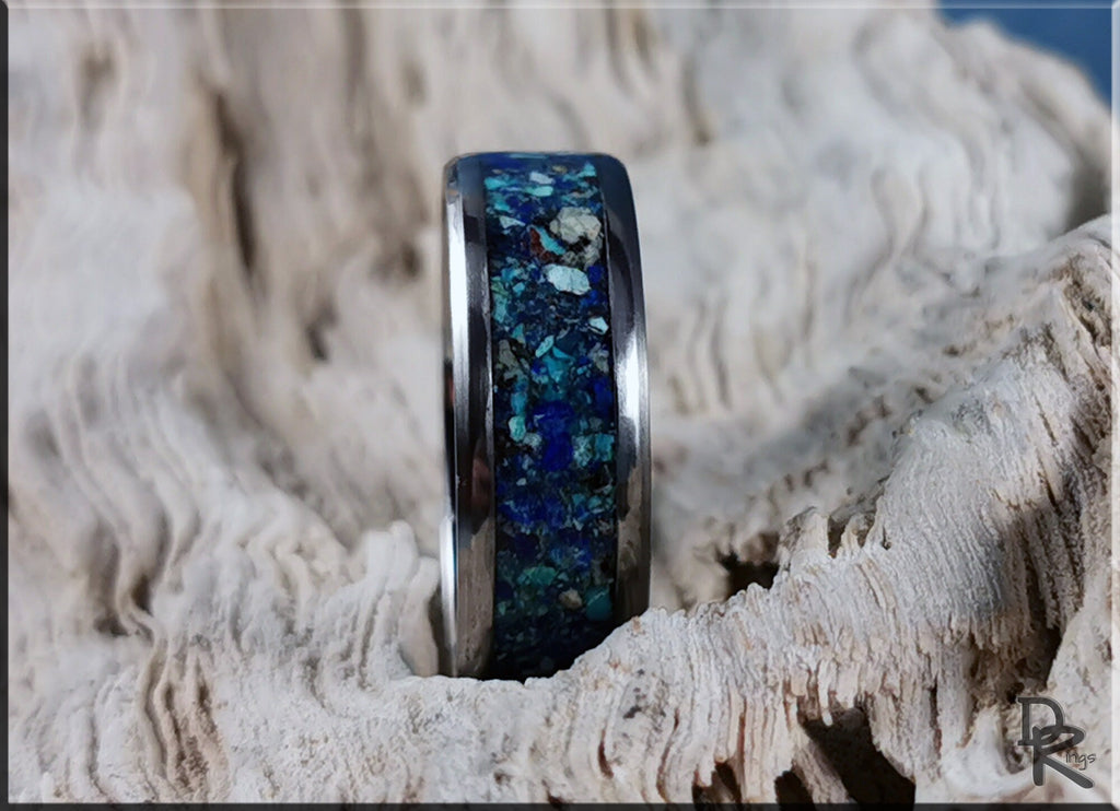 Titanium ring with azurite inlay featuring blue and green stone details on textured wood background
