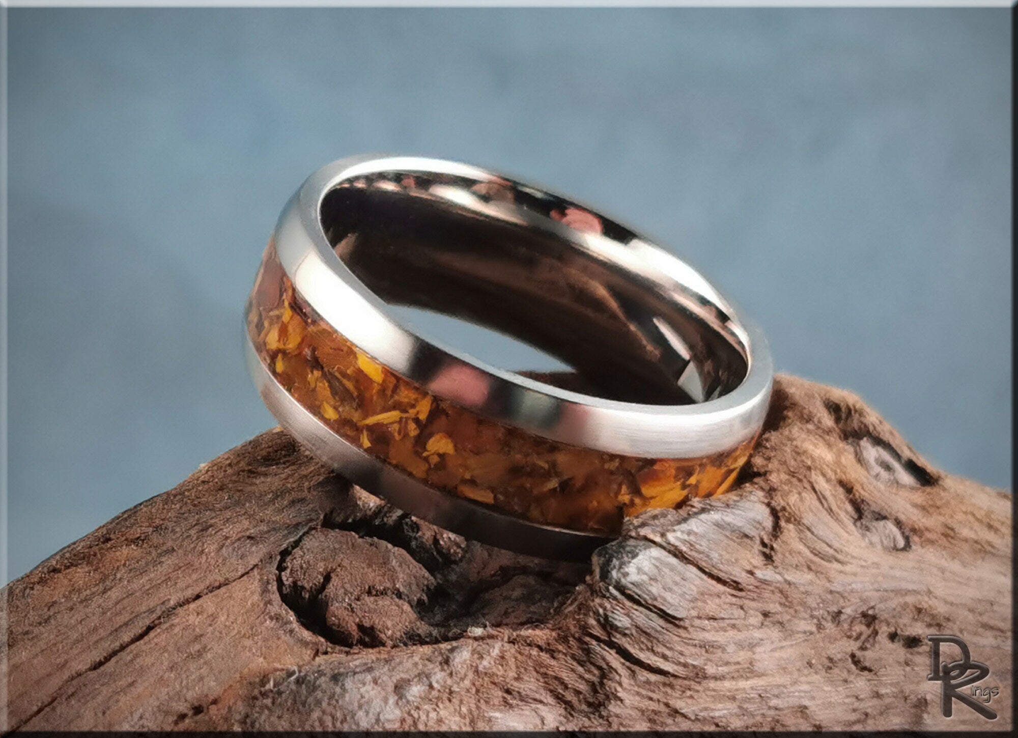 DR Rings titanium ring with inlay featuring amber stone set on natural wood background