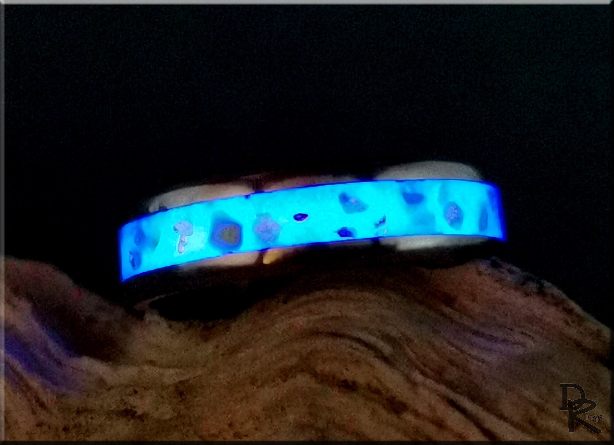 DR Rings titanium ring with inlay glowing blue with unique pattern on wooden surface