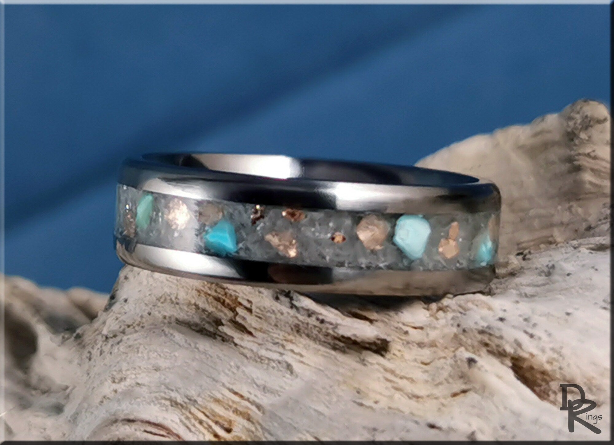 DR Rings titanium ring with inlay featuring blue and silver stone accents on wooden background