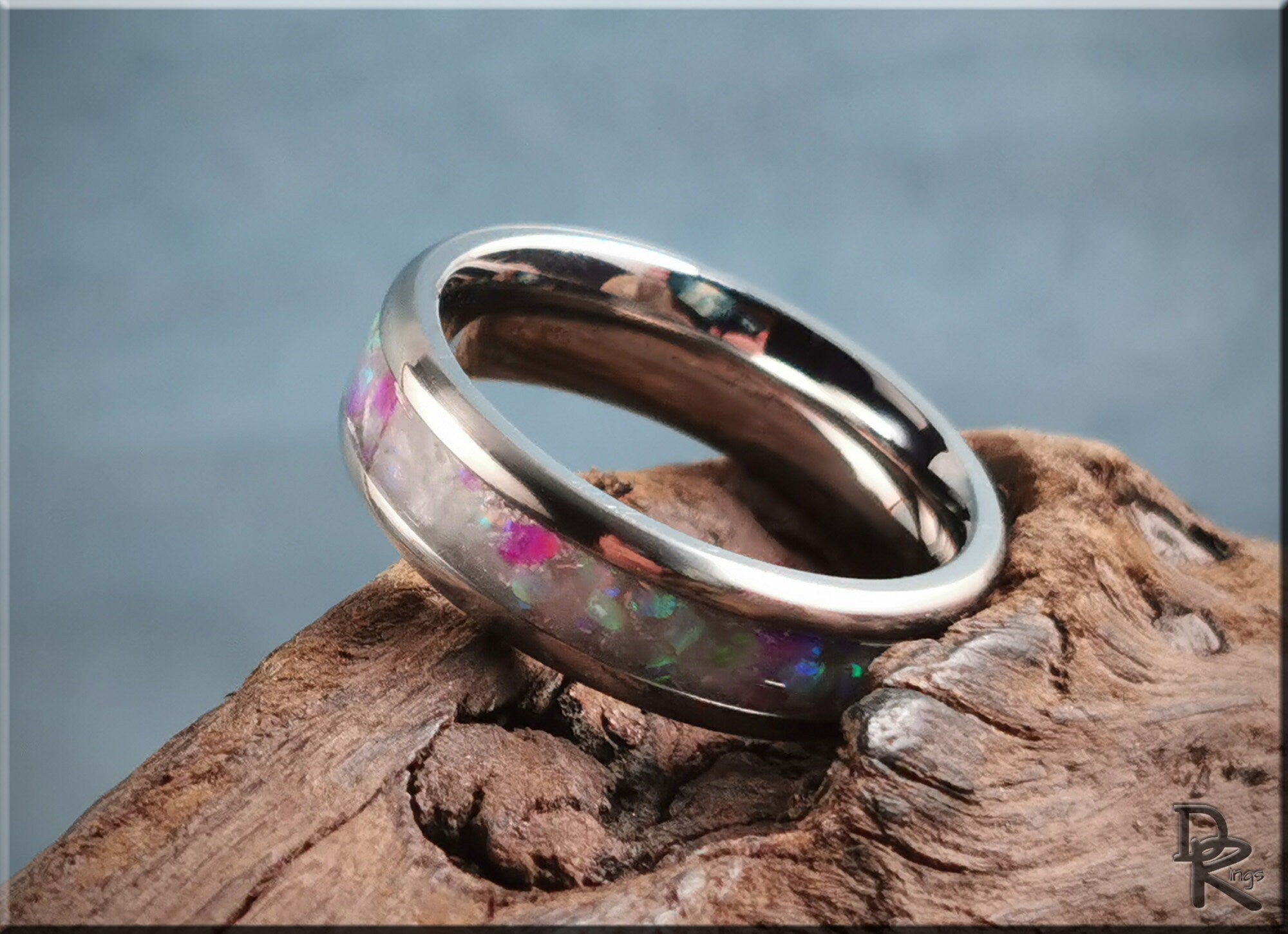 DR Rings titanium ring with inlay featuring colorful opal stone and polished silver finish on wood