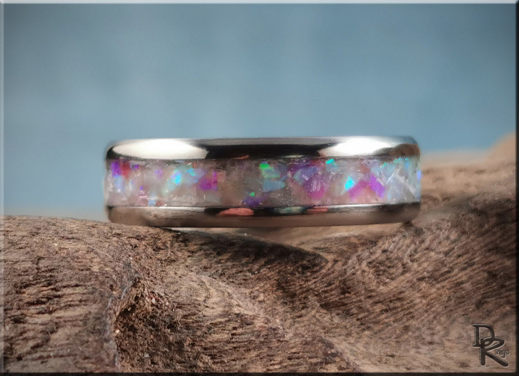 DR Rings titanium ring with inlay featuring colorful iridescent stones on a rustic wooden surface