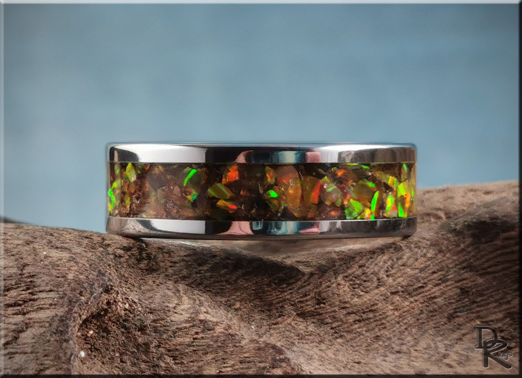 DR Rings titanium ring with inlay featuring vibrant multicolor opal stones on wood background