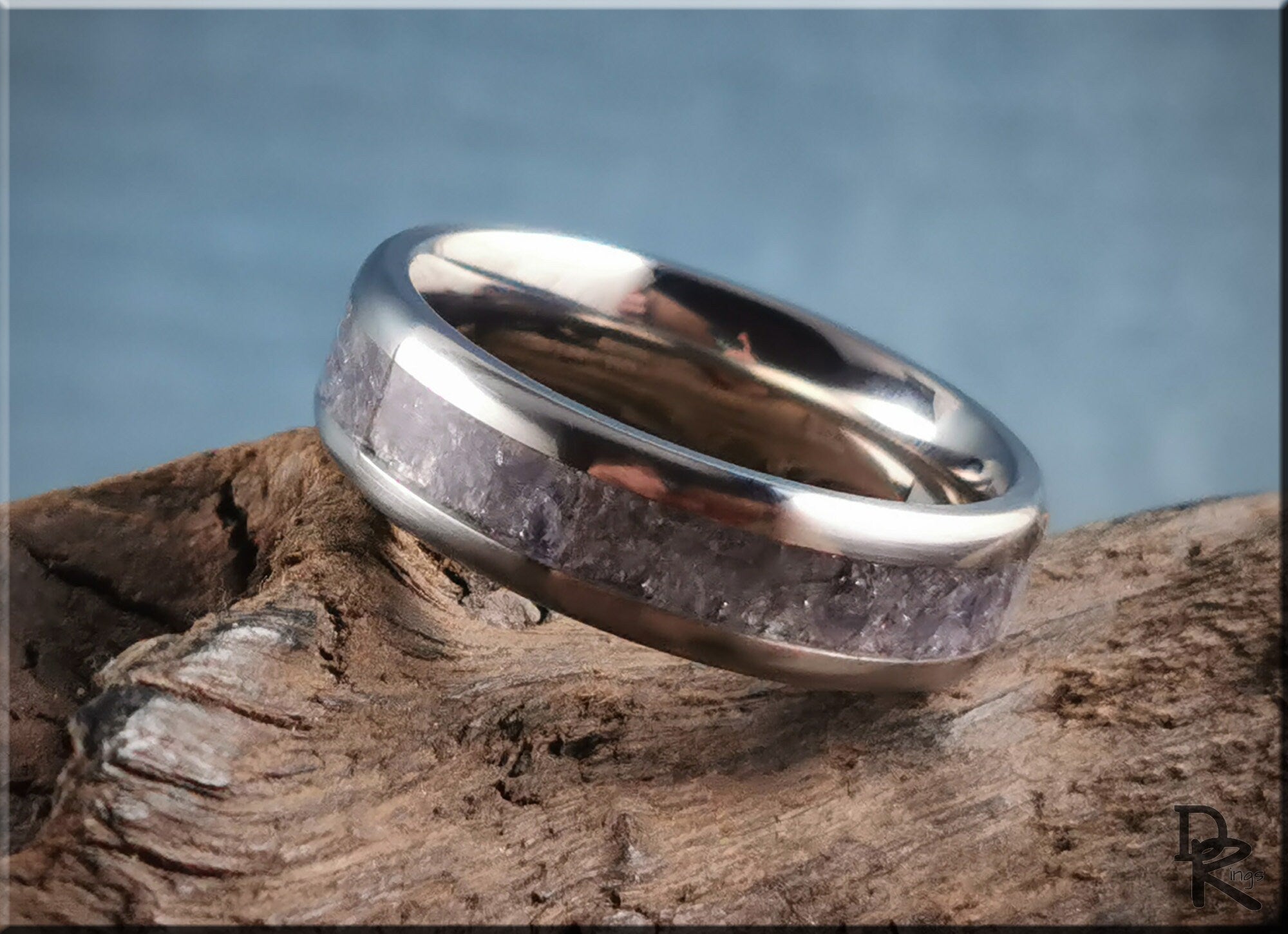 DR Rings titanium ring with inlay featuring a polished silver finish resting on rustic wood