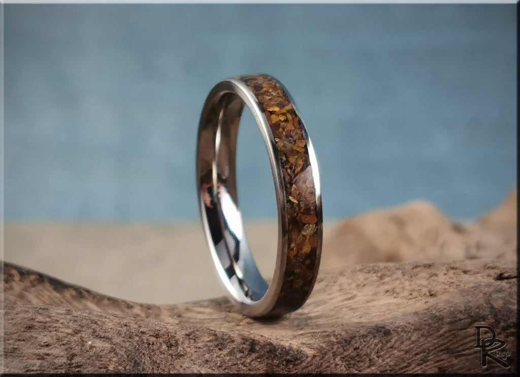 DR Rings titanium ring with inlay featuring a polished brown stone design on a natural wood surface