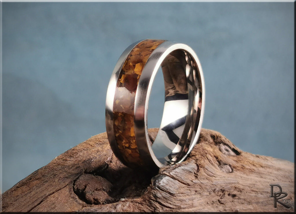 DR Rings titanium ring with inlay featuring polished metal band and amber wood inlay on rustic wood surface