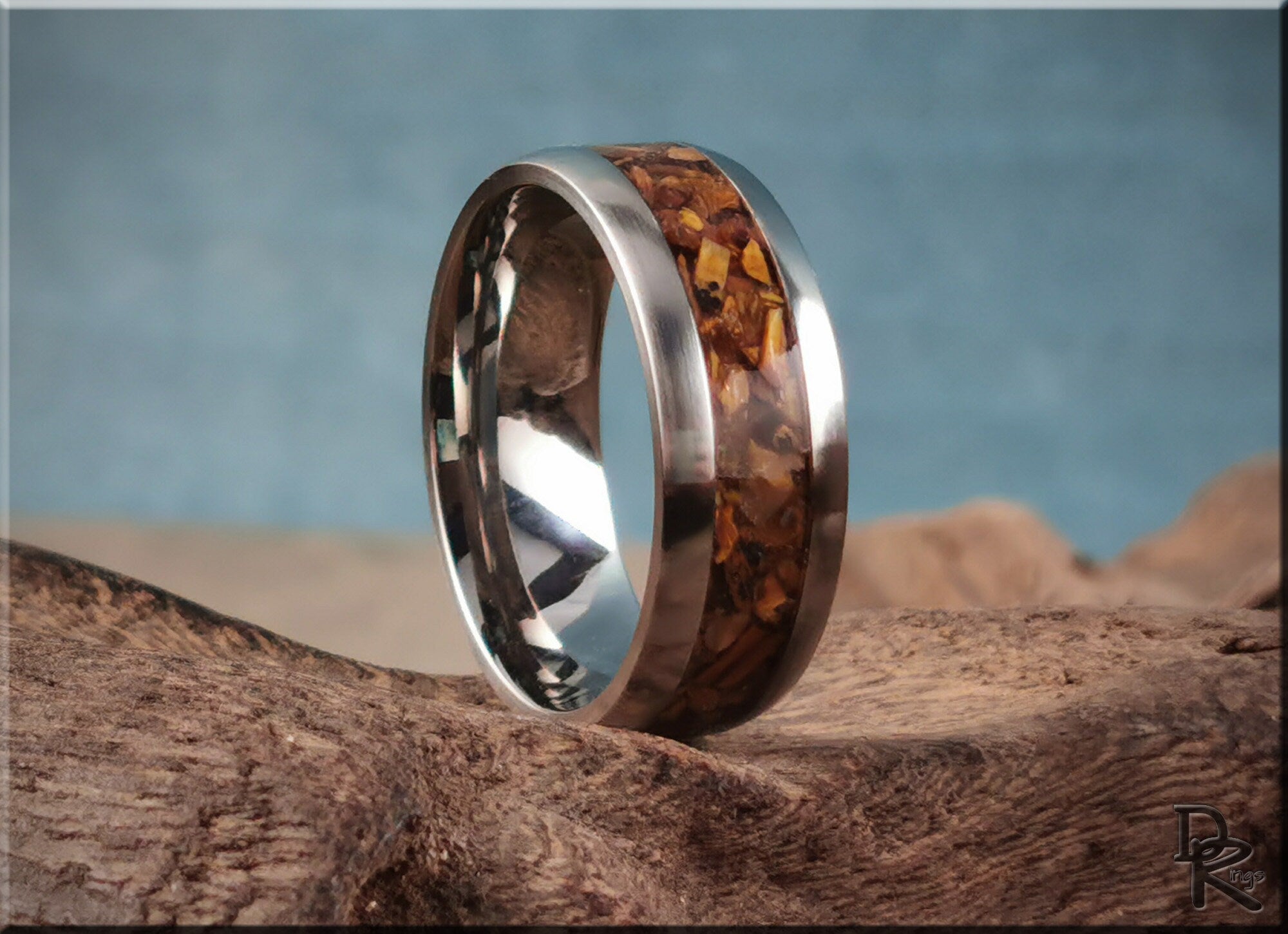 DR Rings titanium ring with inlay featuring brown wood design and polished silver band on rustic wood surface