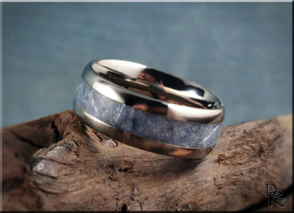 Titanium ring with kyanite inlay resting on textured wood background by DR Rings