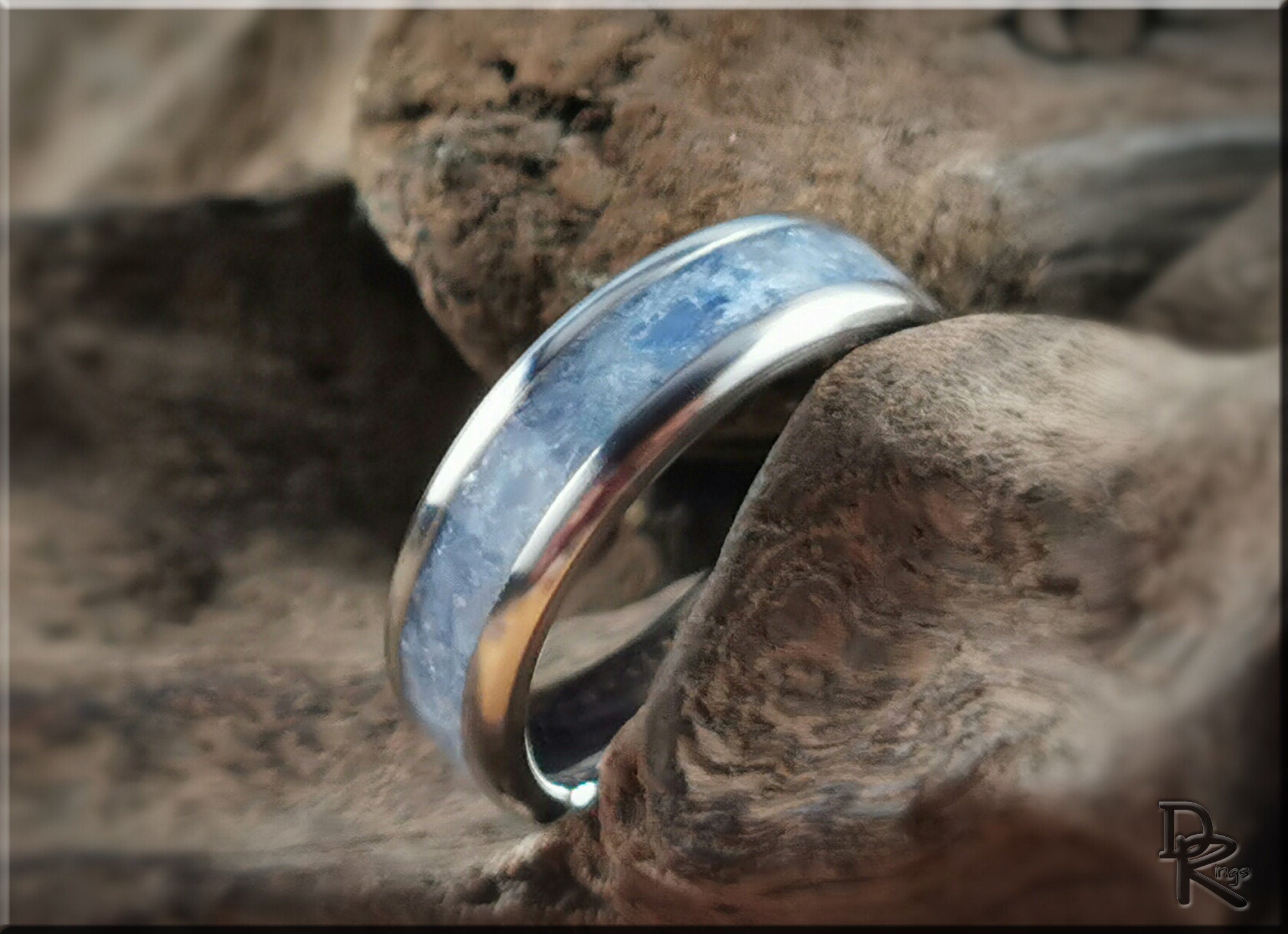 DR Rings polished titanium ring with kyanite stone set in the center on natural wood background