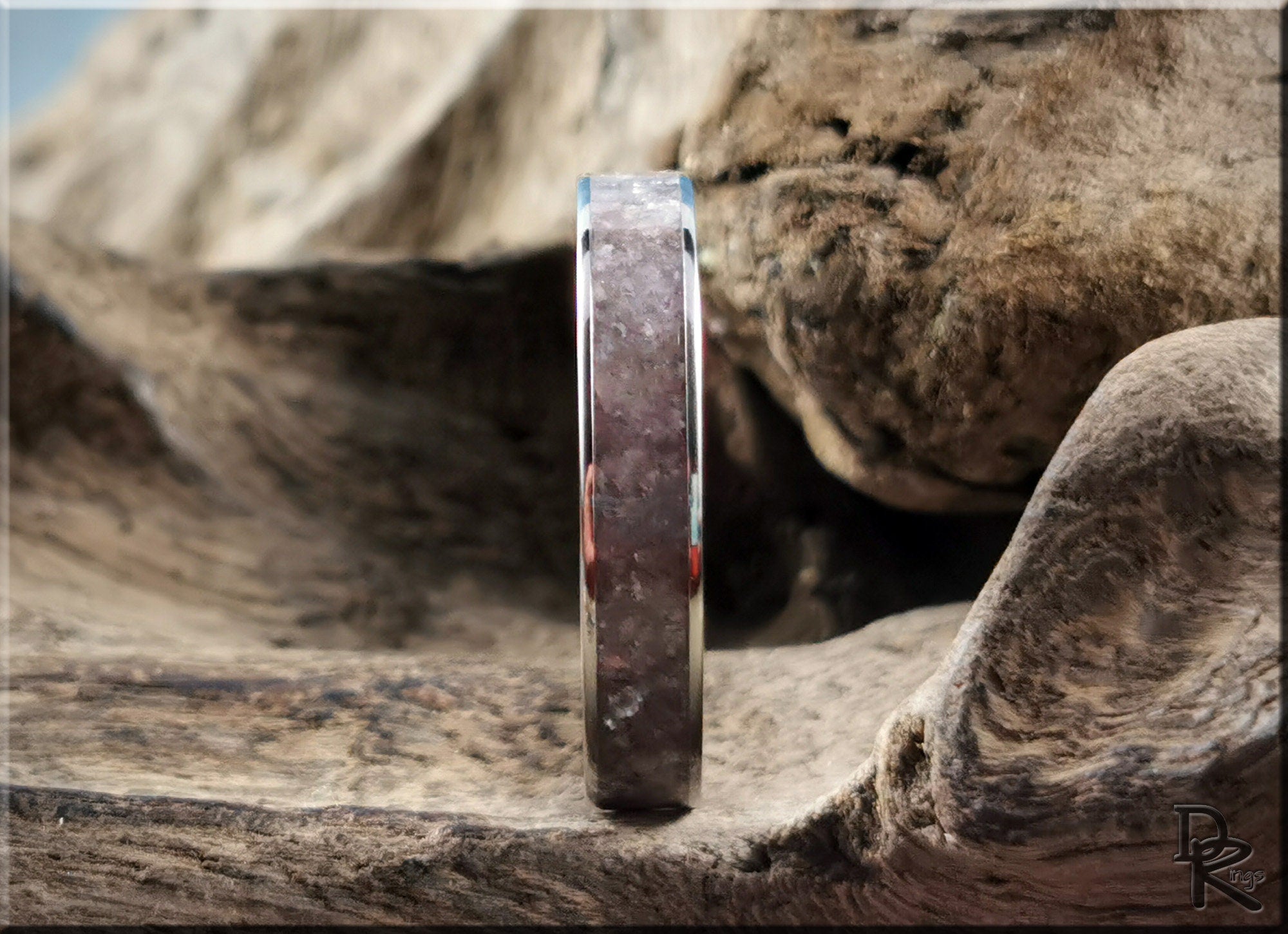 DR Rings titanium ring with lepidolite stone inlay displayed on textured natural wood
