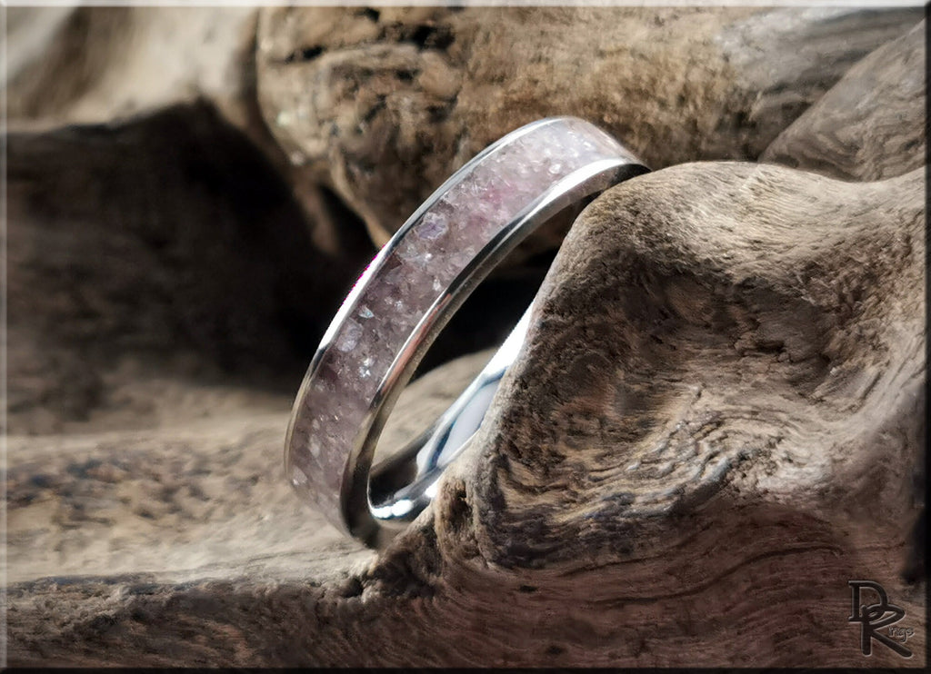 Titanium ring with lepidolite inlay resting on textured wood surface by DR Rings