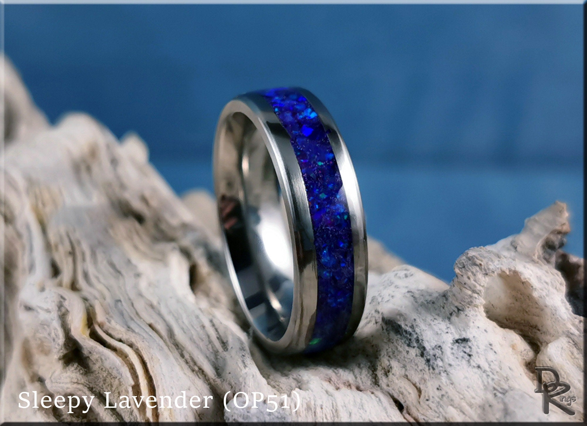DR Rings titanium ring with opal inlay featuring deep blue stones on a natural wood background