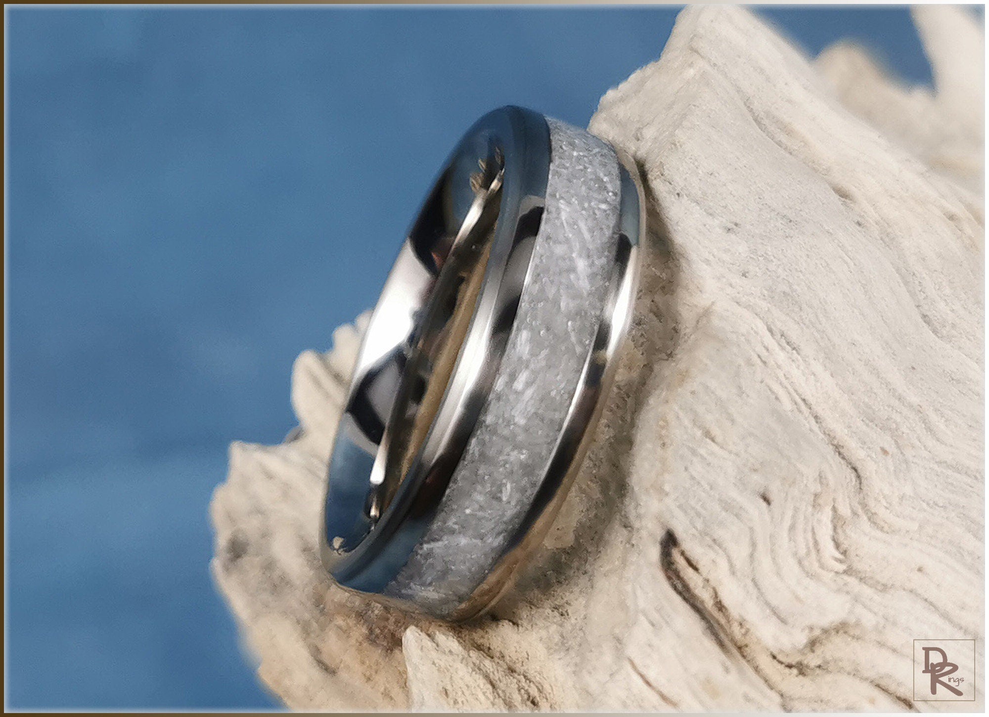 Titanium ring with selenite inlay resting on textured light wood with blue background