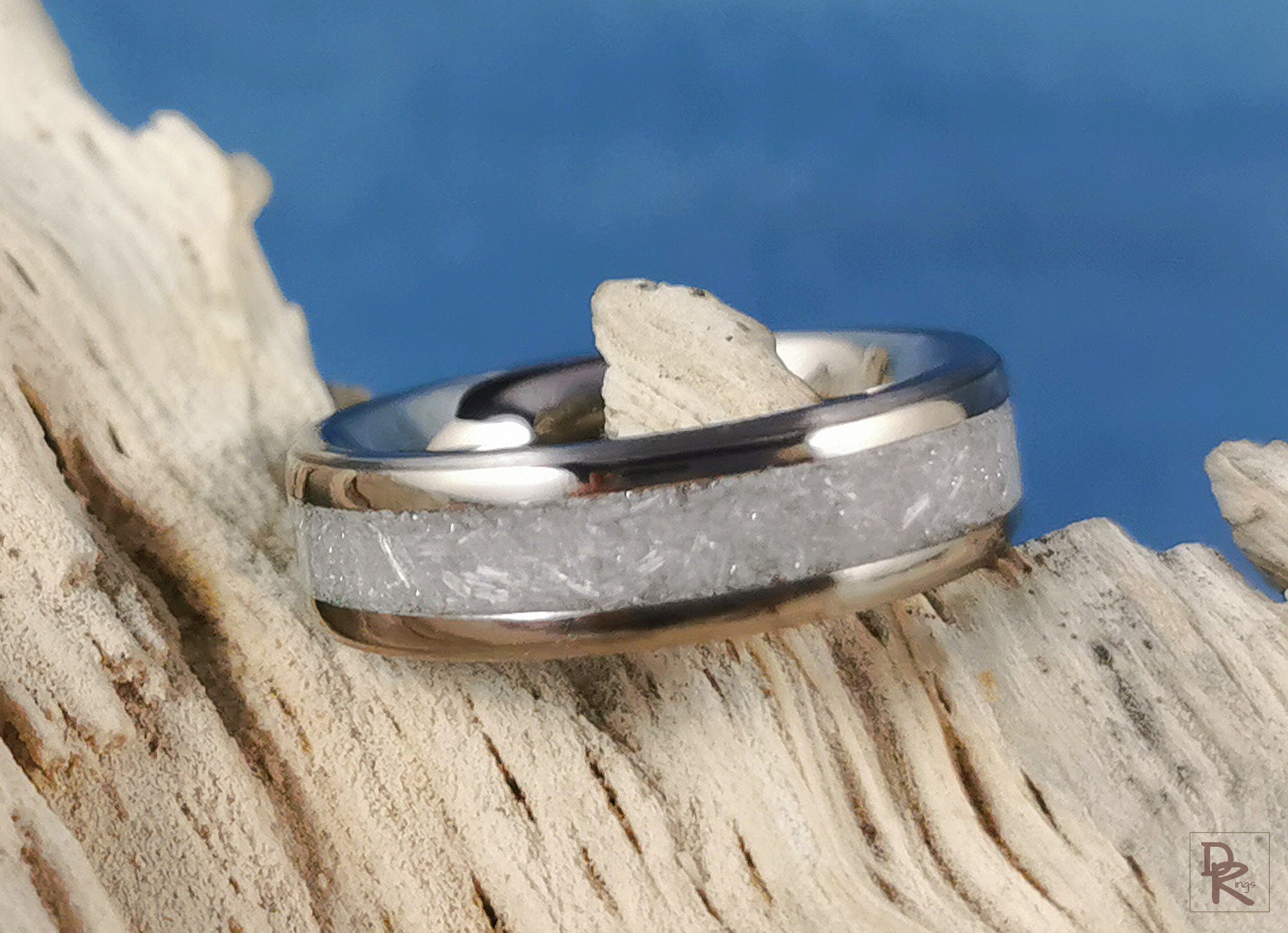 DR Rings titanium ring with selenite inlay on textured wood background with blue backdrop