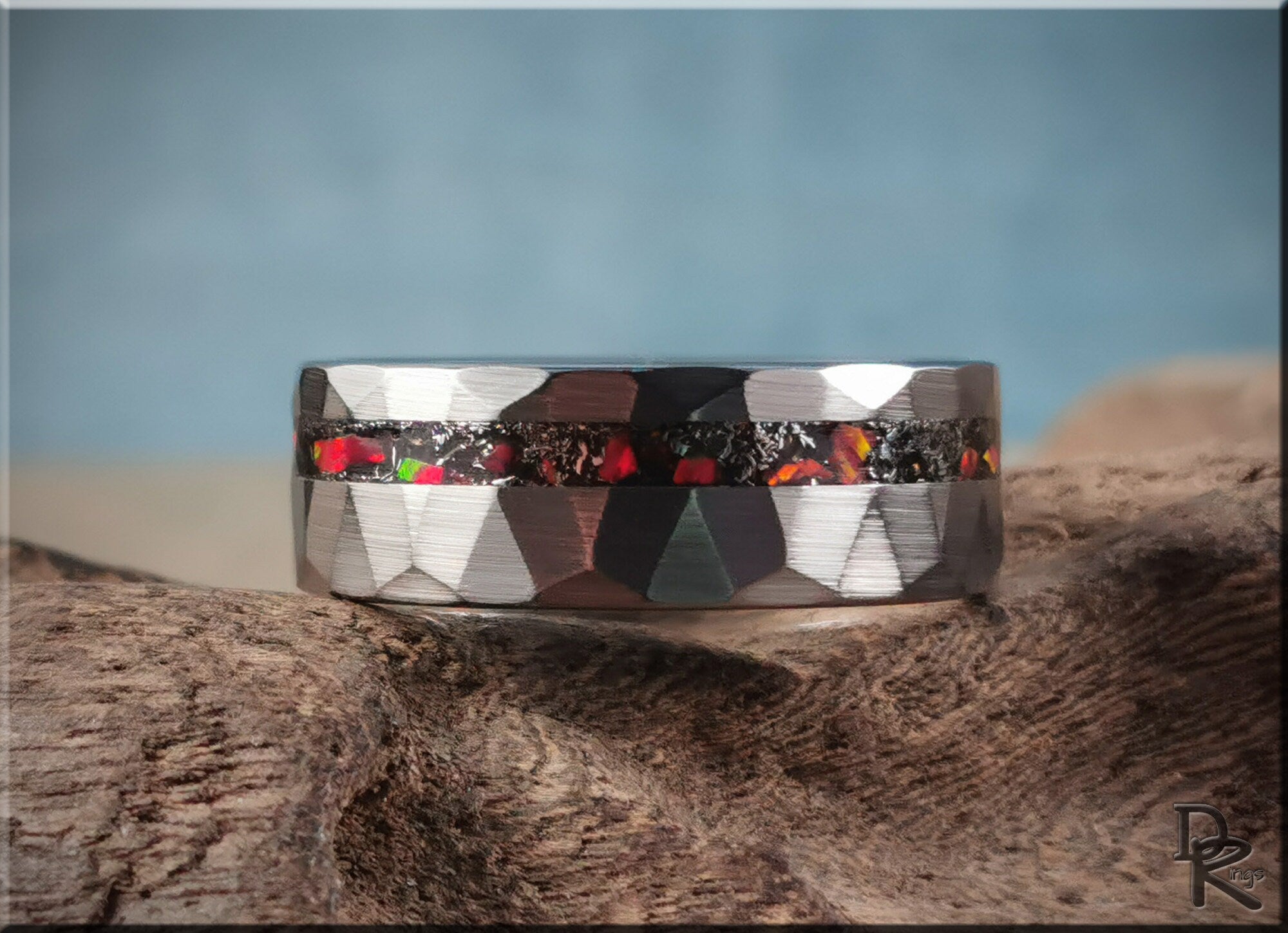 DR Rings tungsten as a ring with faceted silver finish and colorful opal inlay on textured wood background