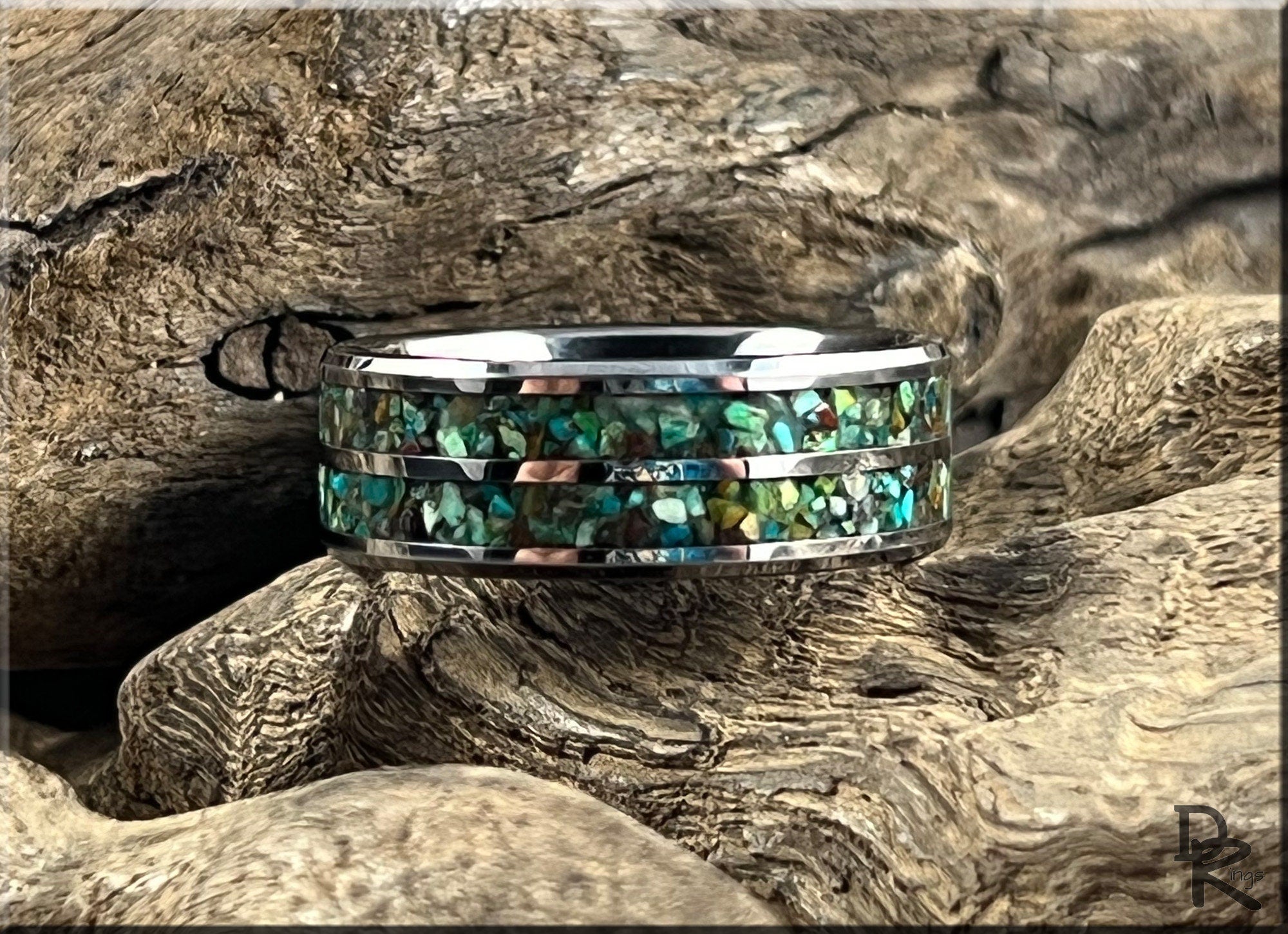 DR Rings tungsten carbide ring with two inlays featuring blue and green stone accents on textured wood background