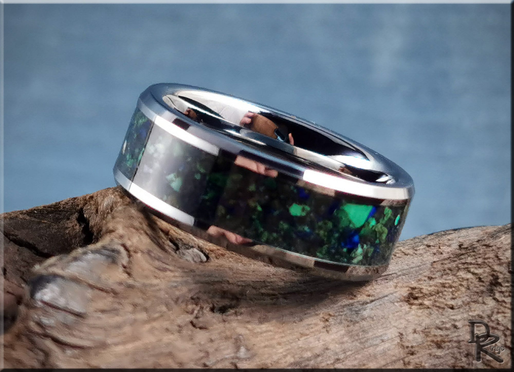 DR Rings tungsten ring carbide with blue and green inlay on a rustic wooden surface