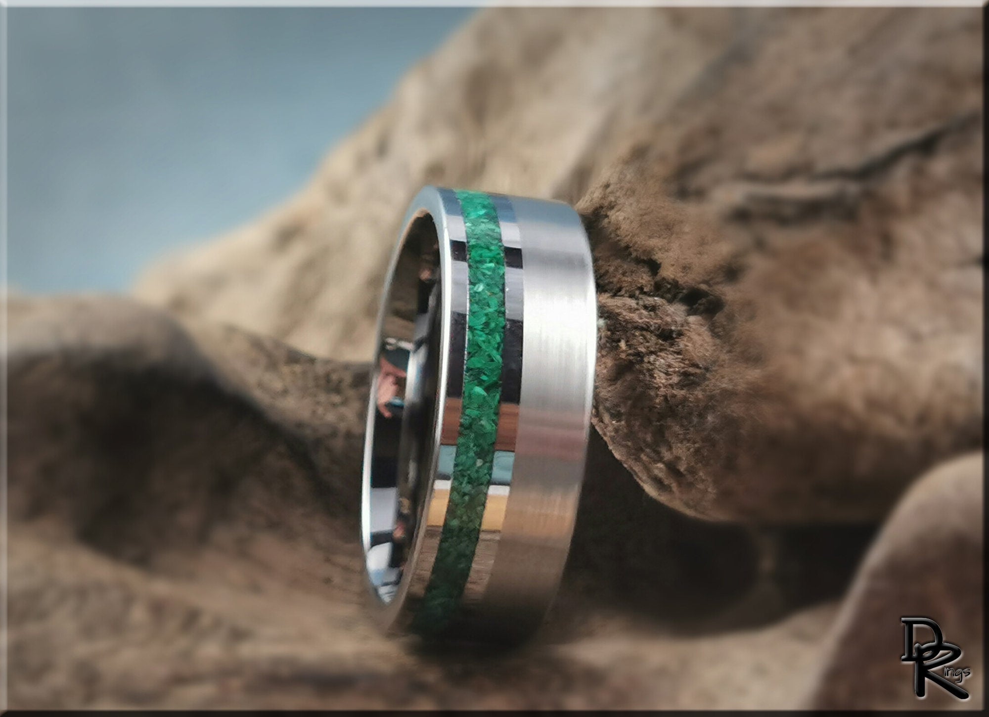 DR Rings tungsten ring carbide with green inlay on a textured natural rock background